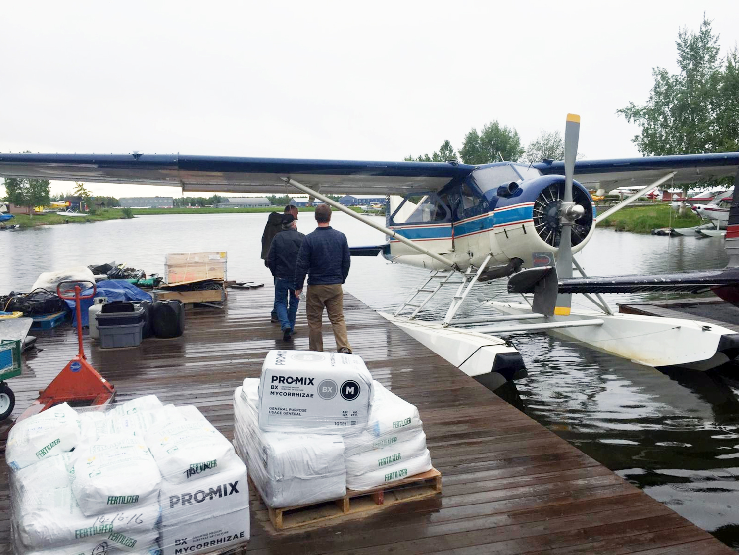Photo of Nova and Rainy Pass Lodge personnel working together to bring in Lodge supplies on another Nova chartered aircraft.