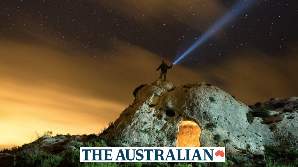 Image of a person on top of hill with a flash light